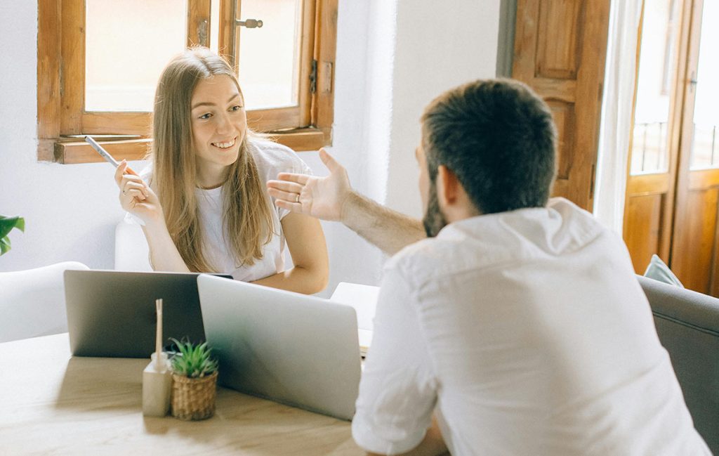 man talking to women sitting on table with laptops